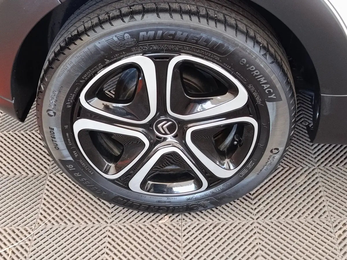 Gros plan sur la roue avant droite d'une Citroën C3 blanche, mettant en valeur la jante noire et argentée au design moderne.
