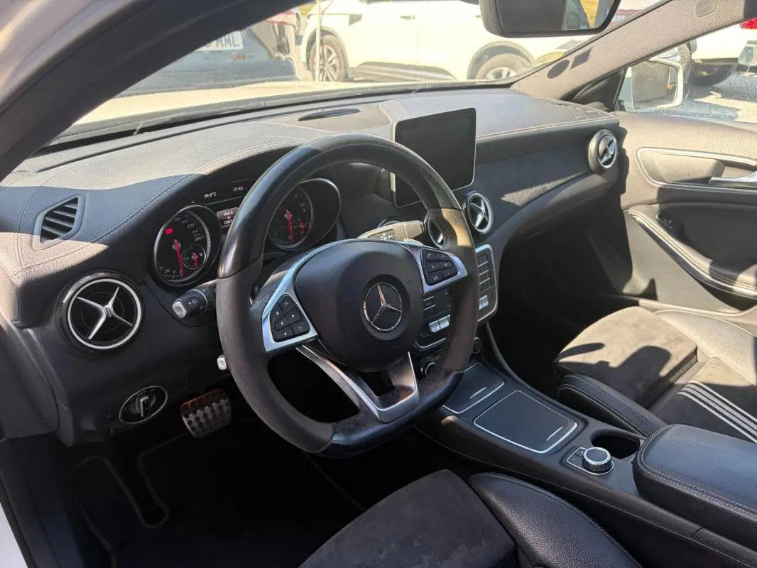 Vue intérieure côté conducteur du Mercedes GLA 220d White Art Edition 2017, tableau de bord noir avec volant multifonction et écran central.