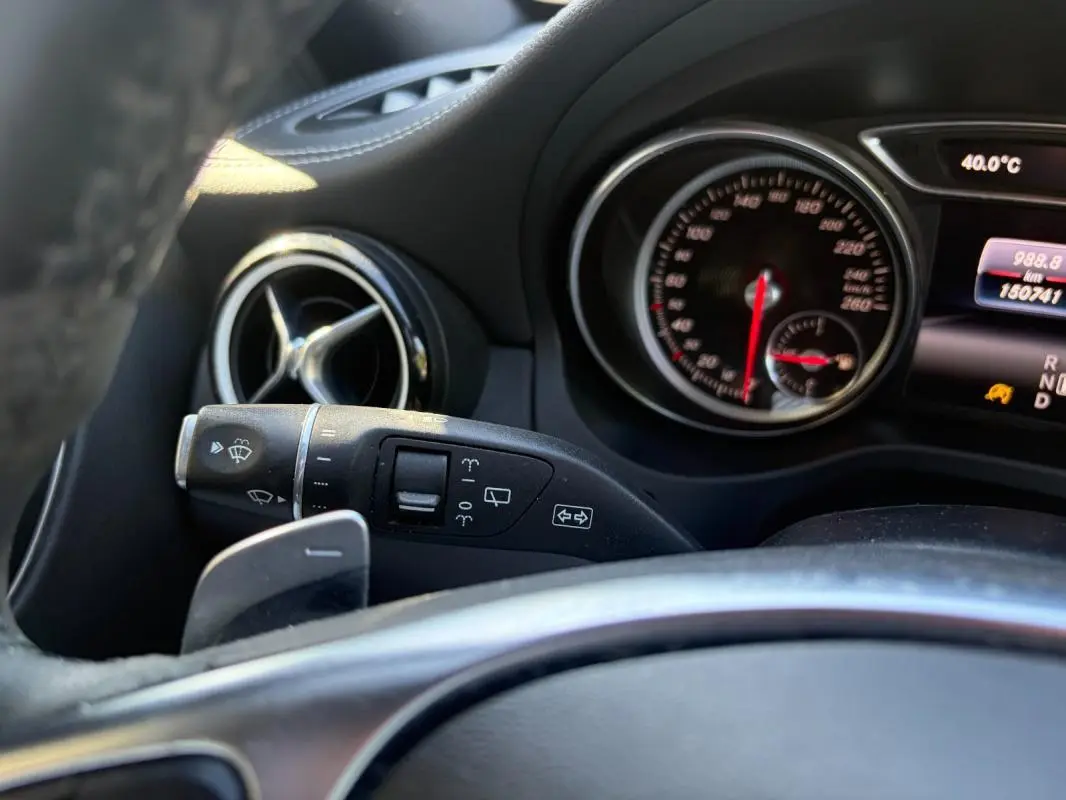 Gros plan sur le combiné d'instruments et la commande d'essuie-glace côté gauche du tableau de bord du Mercedes GLA blanc 2017.