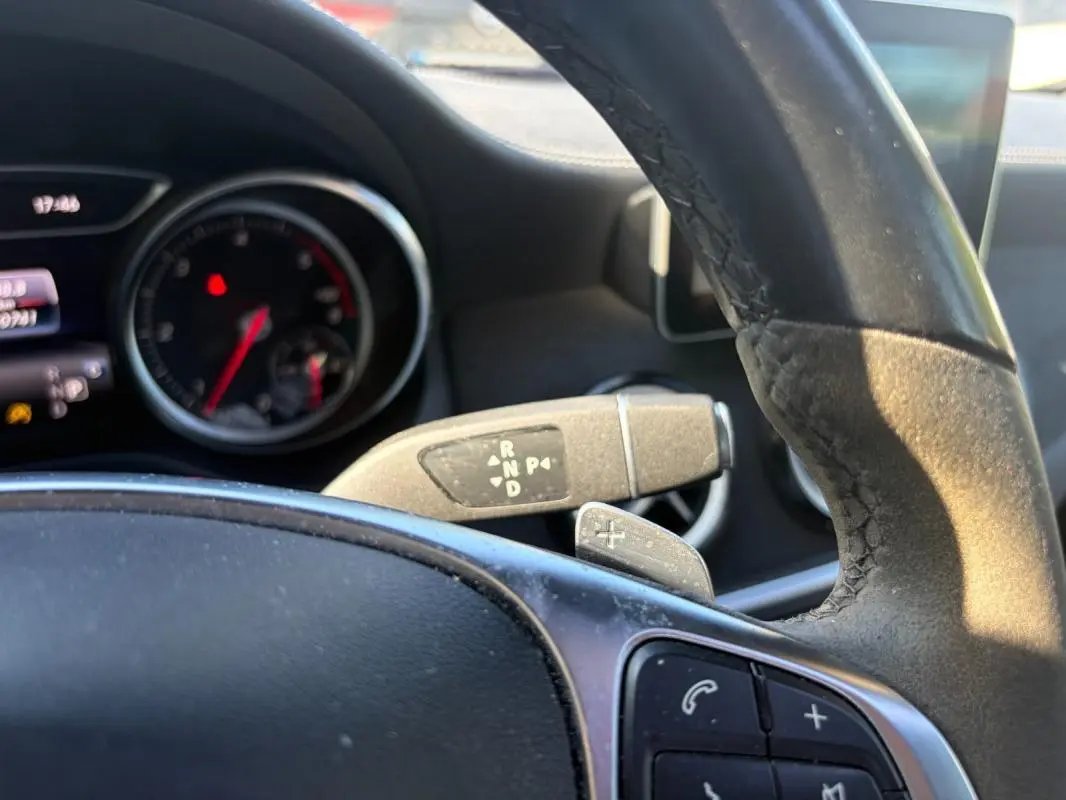 Vue intérieure rapprochée du volant et du levier de vitesses automatique d’un Mercedes GLA 220d blanc de 2017.
