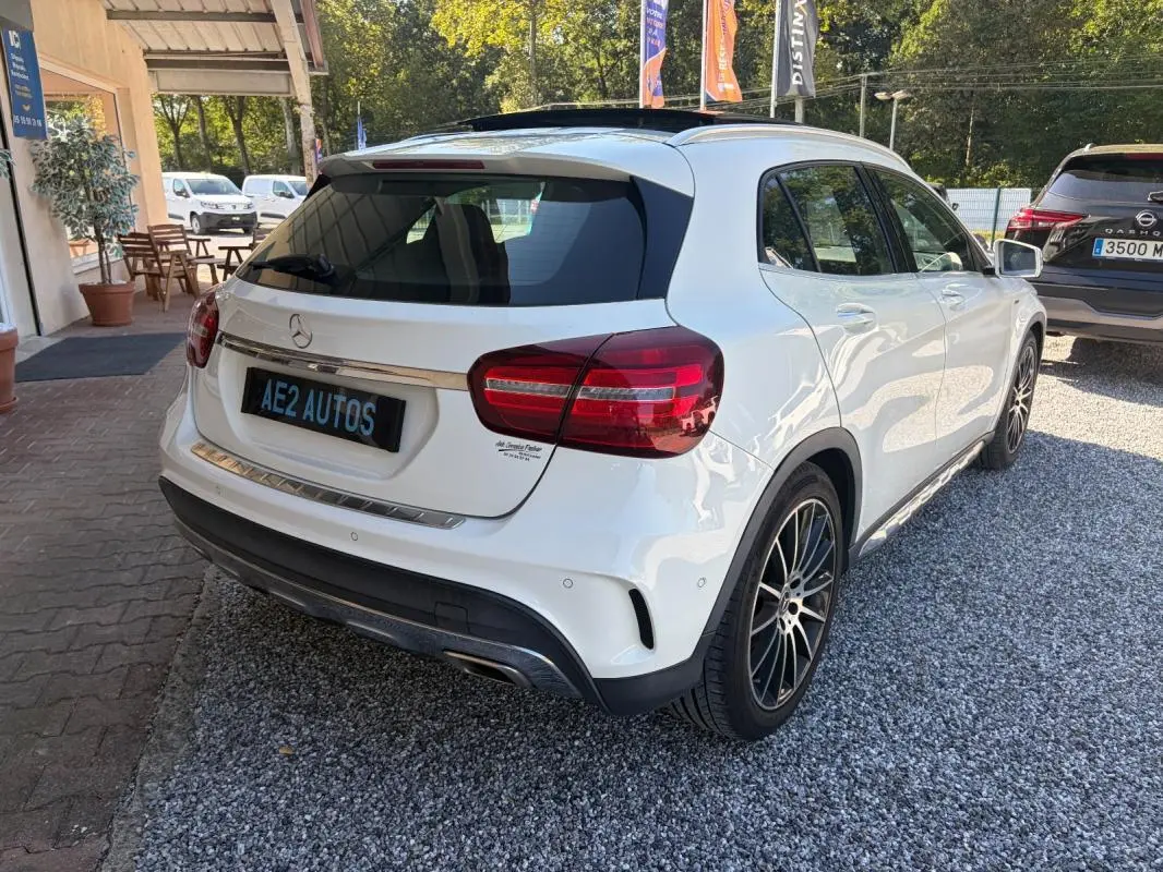 Vue 3/4 arrière droite d'une Mercedes GLA 220d blanche, avec jantes noires et détails chromés sur le hayon.