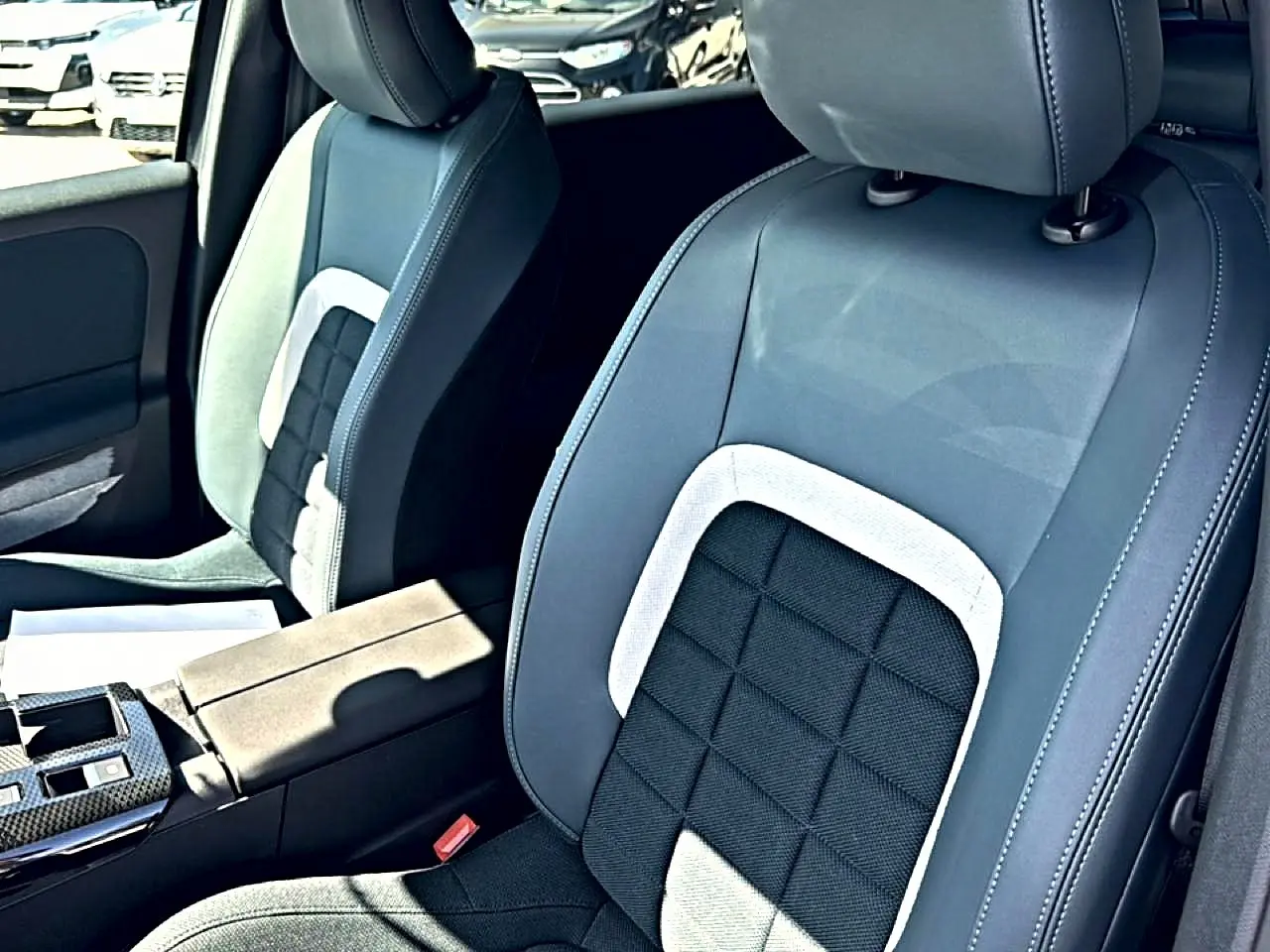 Vue rapprochée des sièges avant gris et noirs avec accoudoir central dans un Citroën C5 Aircross hybride 2026.