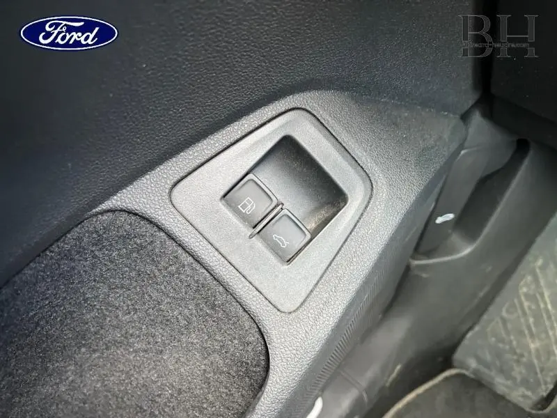 Gros plan sur les boutons d'ouverture de la trappe à carburant et du coffre dans l'habitacle noir du Volkswagen Tiguan.