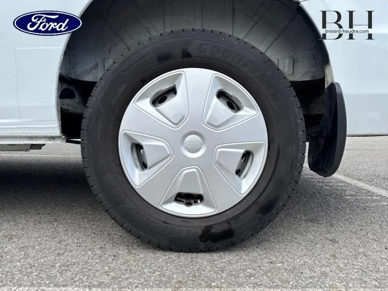 Gros plan sur la roue avant droite du Ford Transit Custom blanc Glacier avec enjoliveur et bavette arrière visible