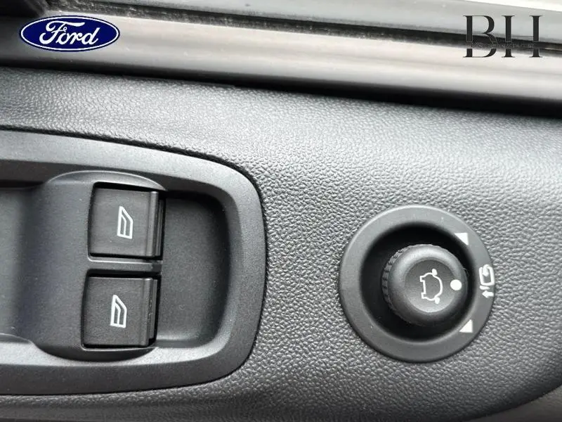 Gros plan sur les commandes de lève-vitres et réglage des rétroviseurs du Ford Transit Custom blanc Glacier 2023.