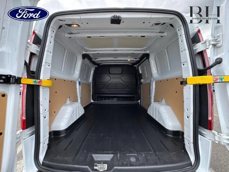 Vue arrière ouverte du fourgon Ford Transit Custom blanc Glacier, montrant l'espace de chargement vide avec plancher noir et cloison pleine noire.