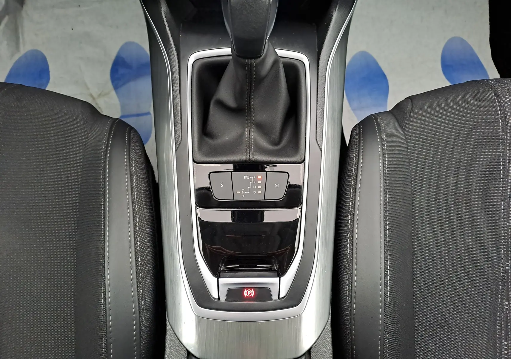 Vue plongeante sur la console centrale de la Peugeot 308 gris, avec levier de vitesse automatique et sièges noirs.