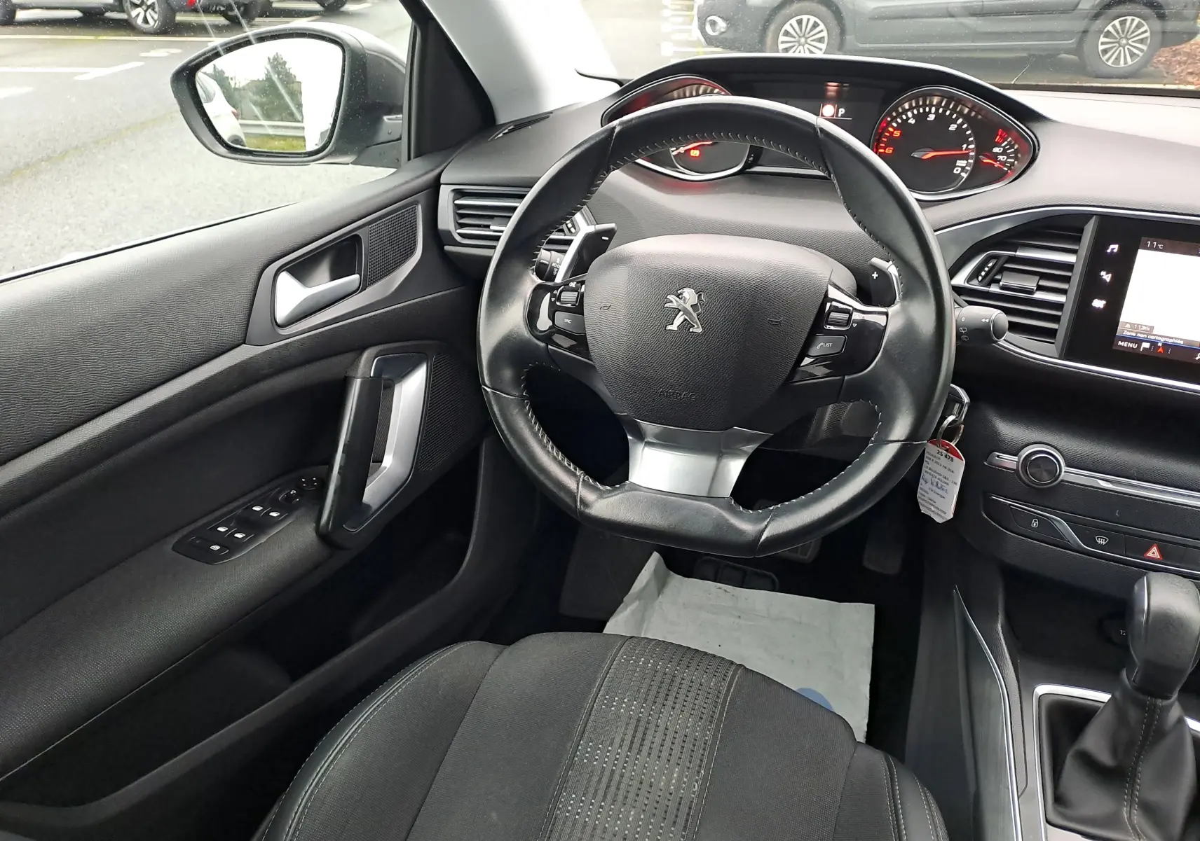 Intérieur noir de Peugeot 308 2019, vue centrée sur le volant cuir avec tableau de bord et écran tactile visibles.