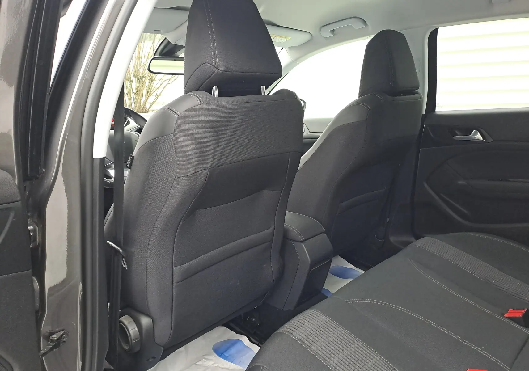 Vue intérieure arrière côté gauche de la Peugeot 308 gris, montrant les sièges noirs en tissu et les portes ouvertes.
