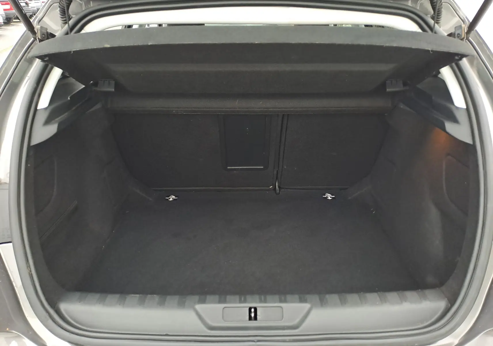 Coffre ouvert d'une Peugeot 308 gris, vue de l'arrière montrant un espace de chargement vide et propre.
