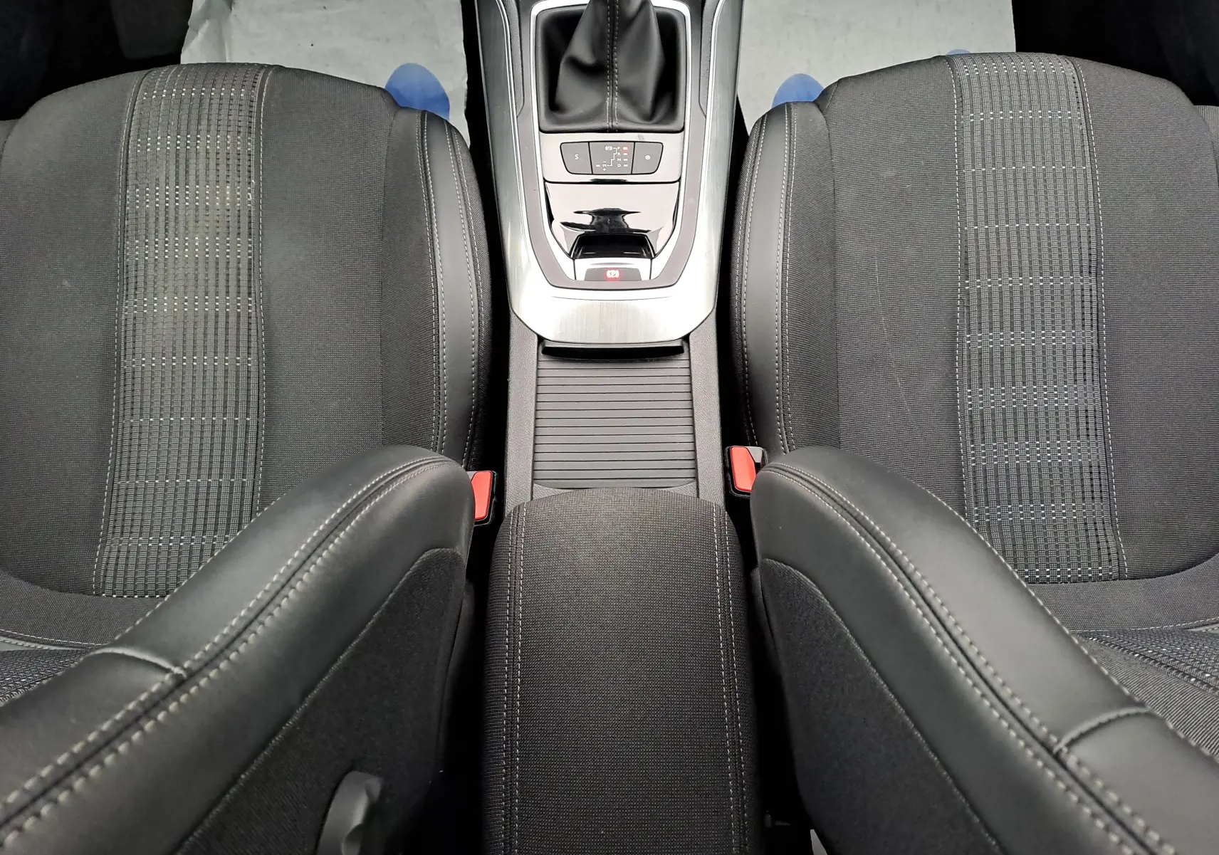 Vue plongeante sur les sièges avant noirs et la console centrale avec levier de vitesse d'une Peugeot 308 gris 2019.