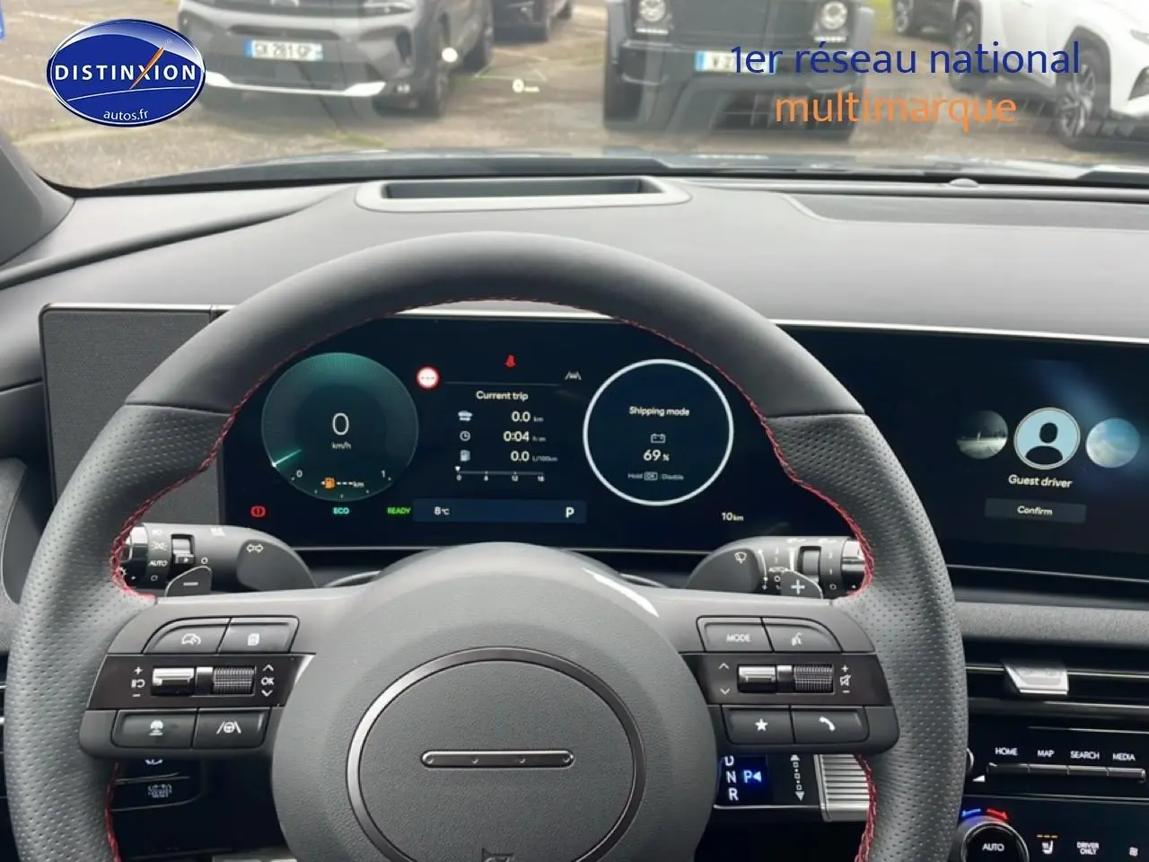 Vue intérieure centrée sur le volant cuir noir N Line avec surpiqûres rouges et tableau de bord digital du Hyundai Tucson gris.