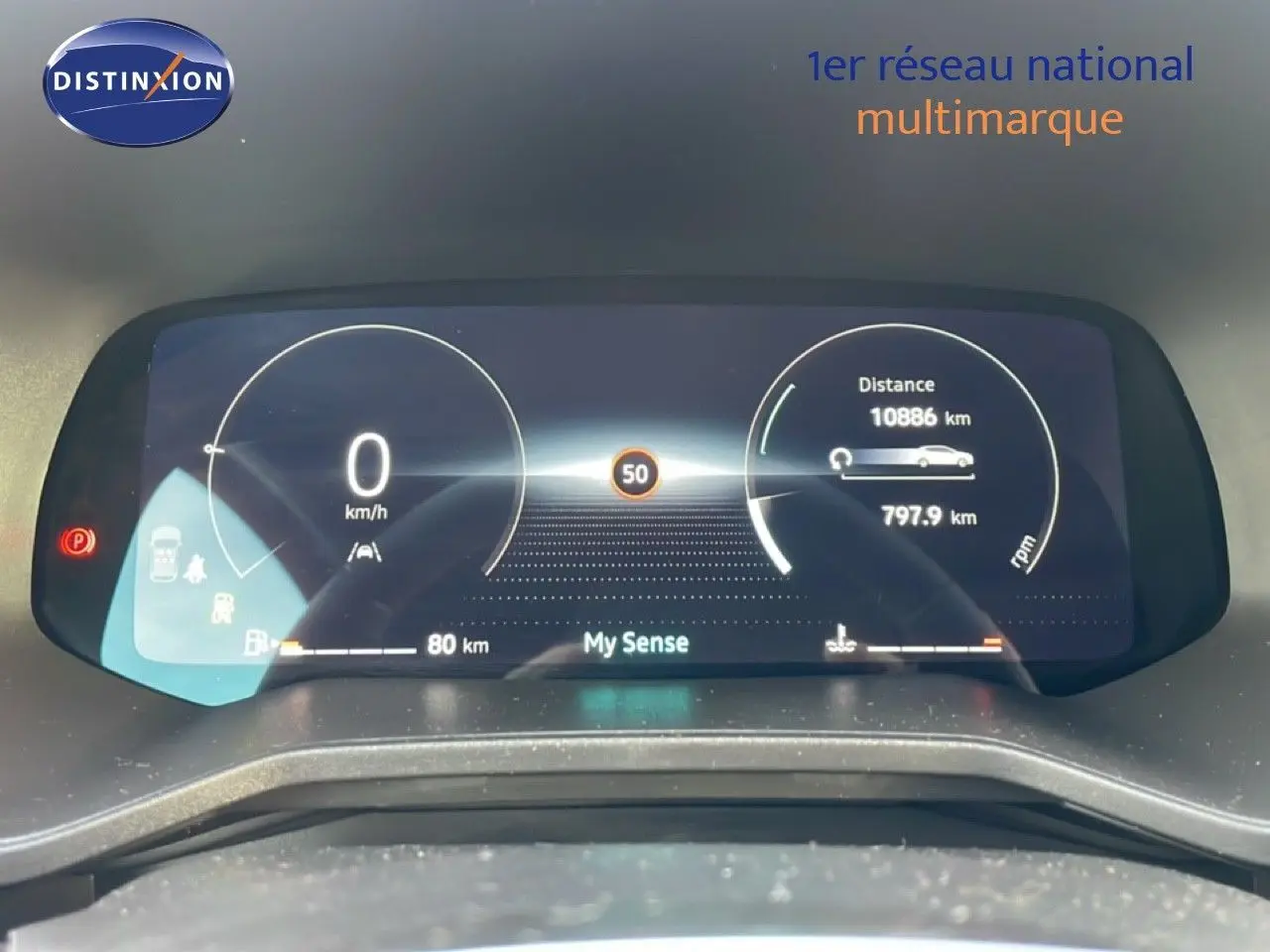 Tableau de bord numérique de Renault Clio rouge, affichant la vitesse à 0 km/h et l'autonomie restante.