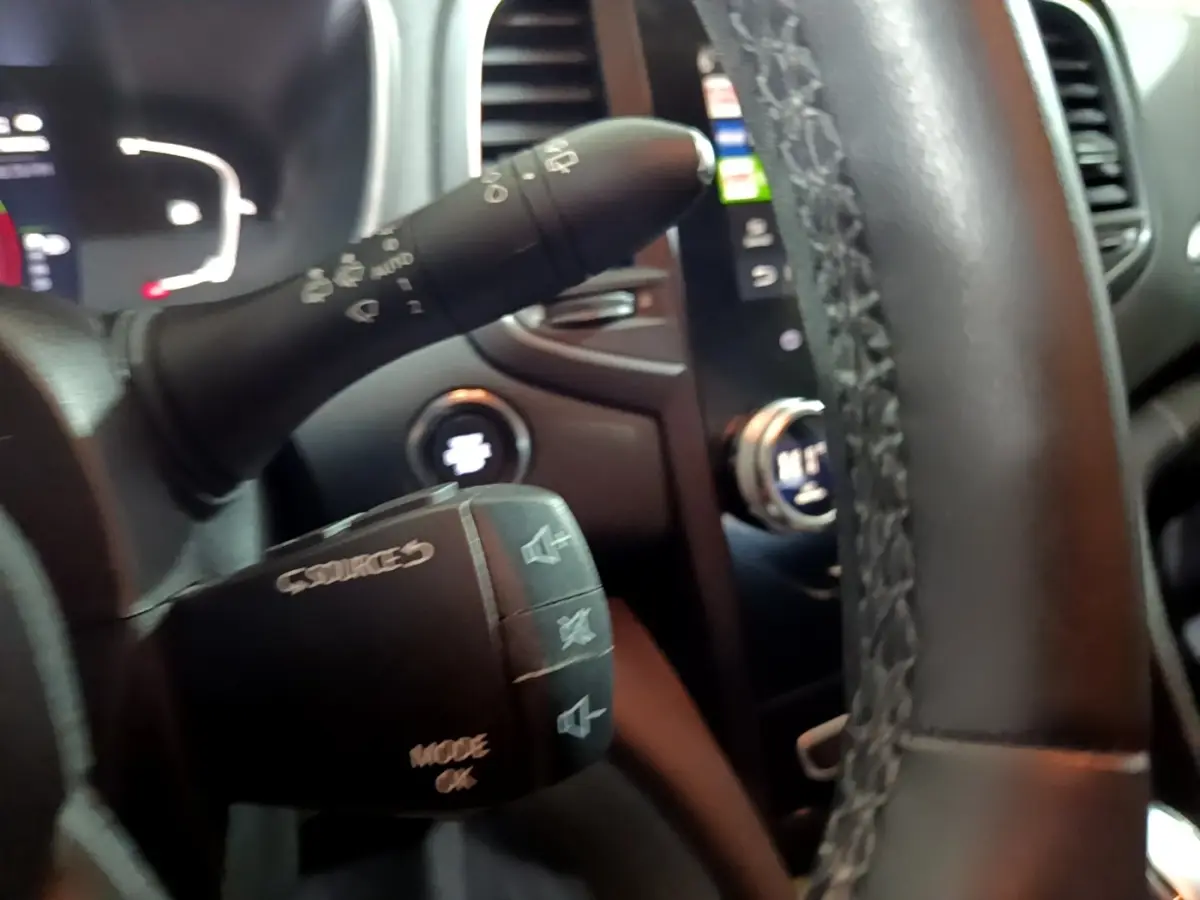 Gros plan sur le volant multifonctions noir de la Renault Mégane Business Blue dCi 115, avec commandes audio visibles.