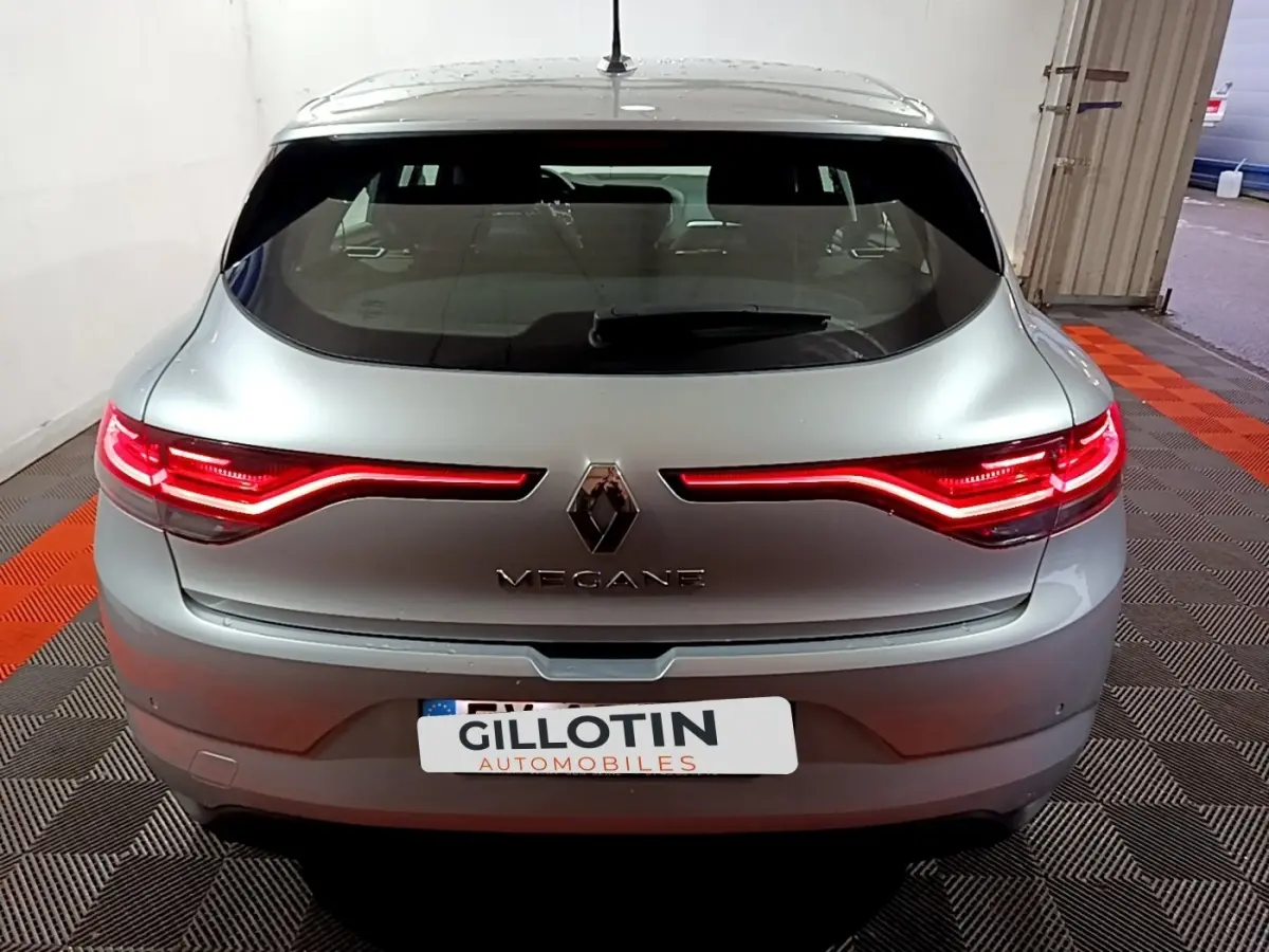 Vue arrière d'une Renault Mégane gris clair avec feux LED allumés dans un garage intérieur.