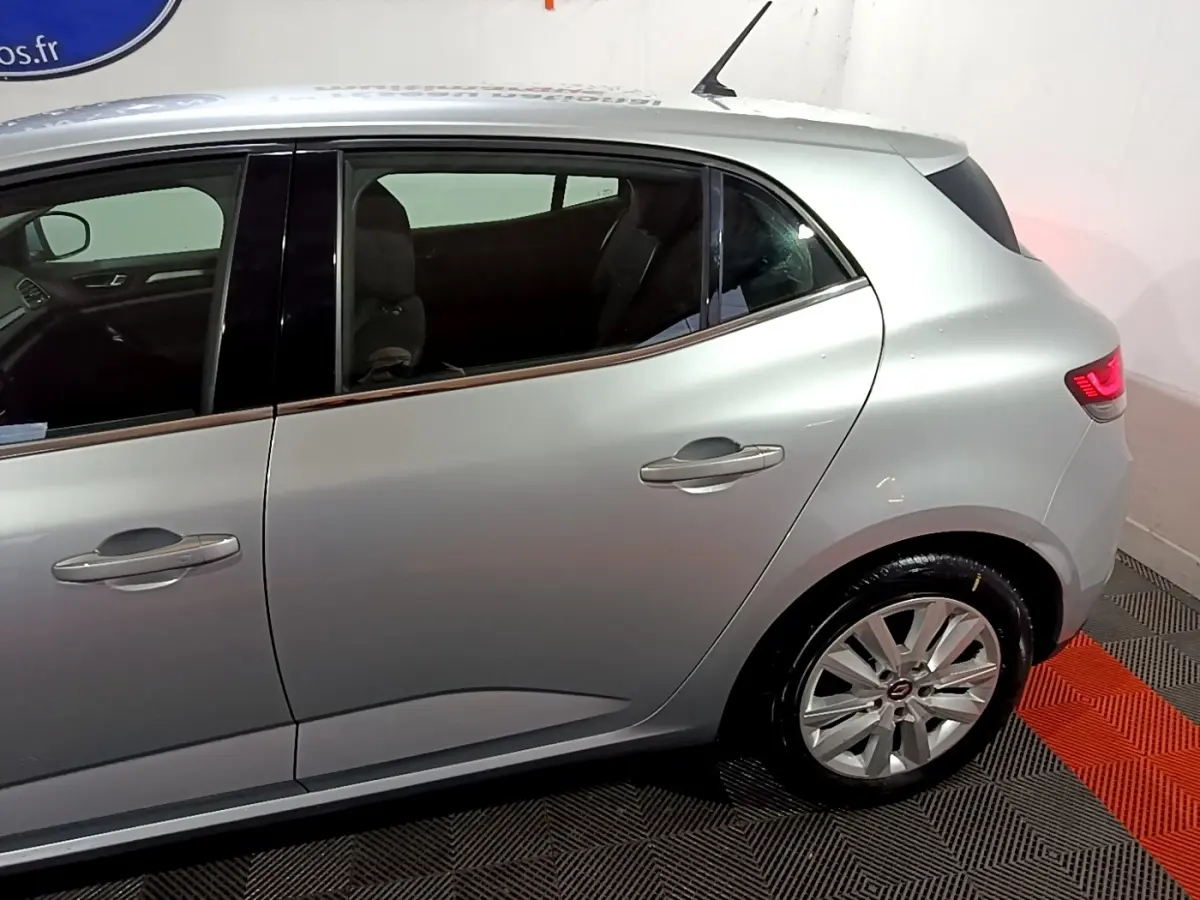 Vue latérale côté droit d'une Renault Mégane Business Blue dCi 115 EDC gris clair avec jantes alliage et feux arrière allumés.