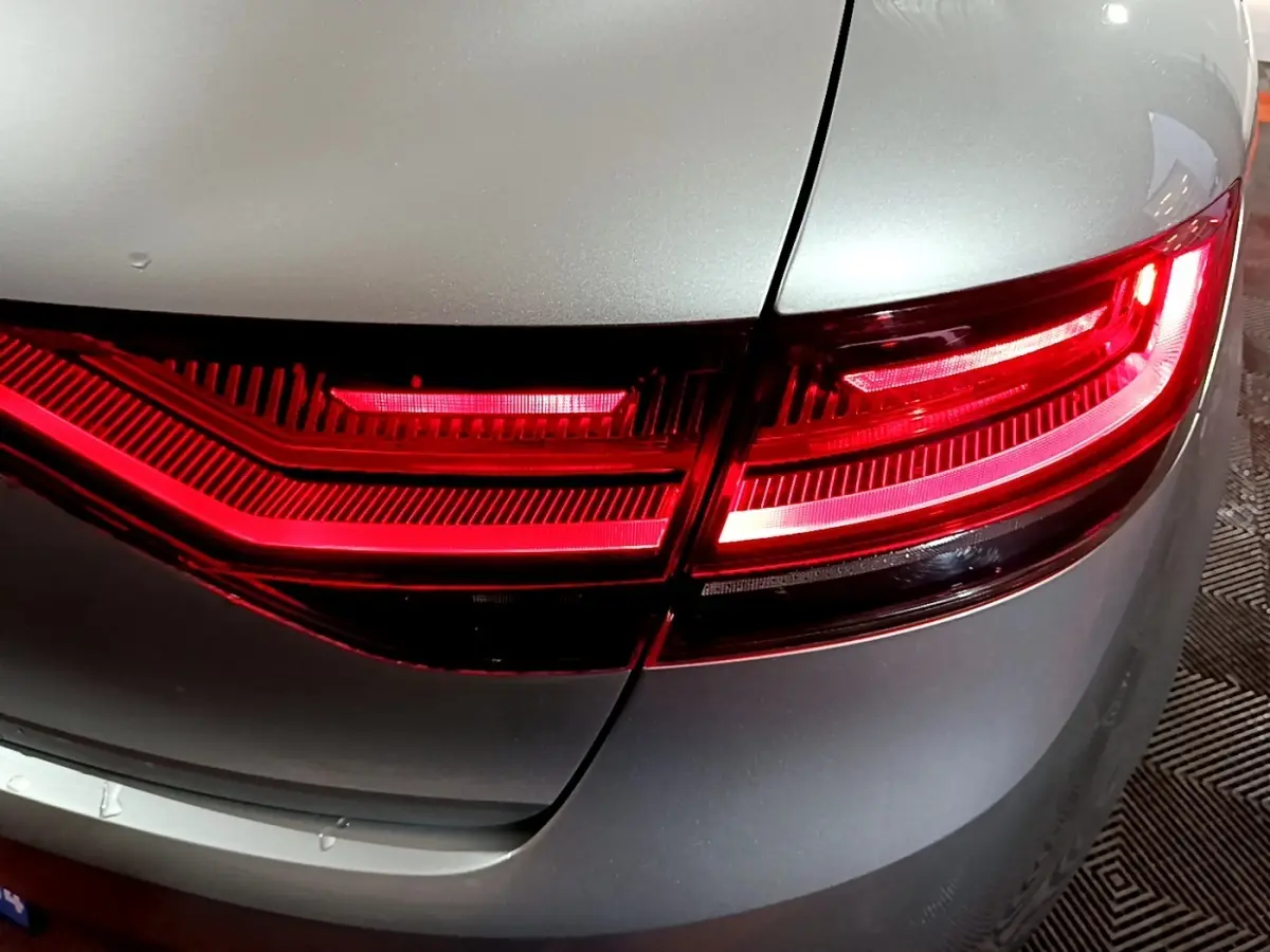 Gros plan sur le feu arrière droit rouge d’une Renault Mégane Business gris clair, vue en léger angle arrière.