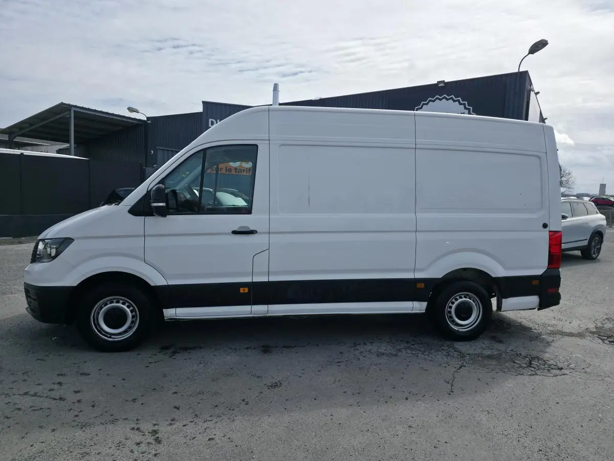 Volkswagen Crafter Fourgon blanc vu de profil côté gauche, avec protections noires sur bas de caisse.