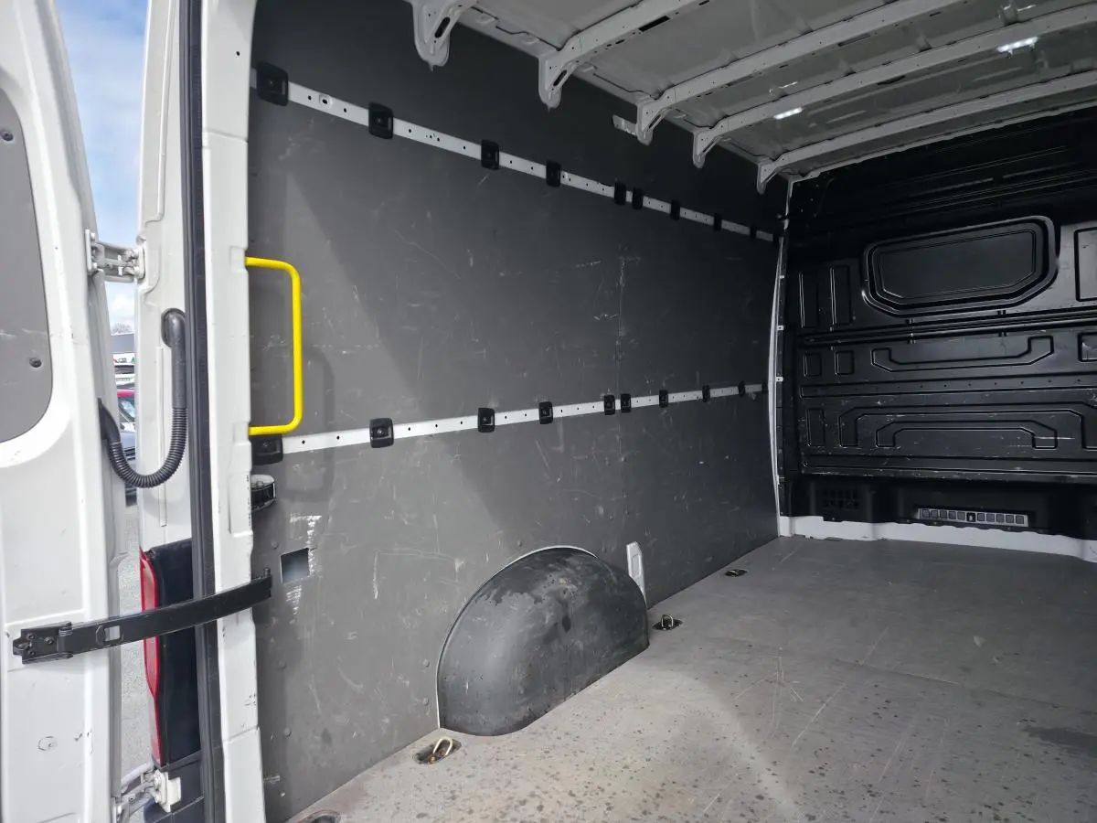 Vue intérieure de l'espace de chargement du Volkswagen Crafter blanc, avec plancher bois et parois grises.