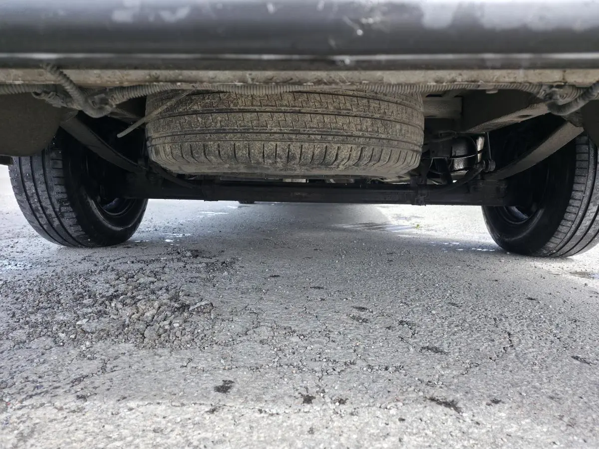 Vue en contre-plongée sous un Volkswagen Crafter blanc, montrant la roue de secours et l'essieu arrière.