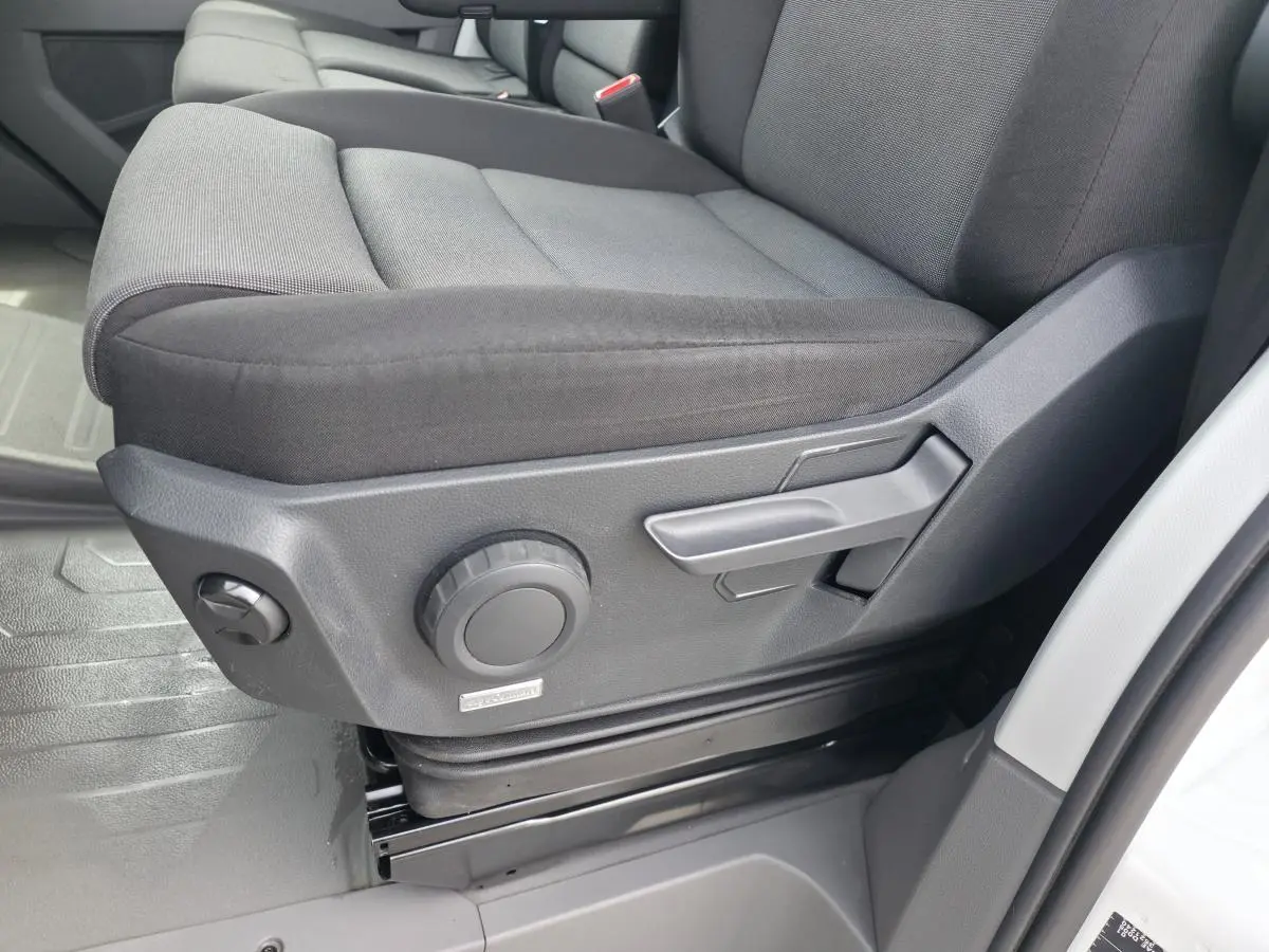 Gros plan sur le siège conducteur gris foncé du Volkswagen Crafter Fourgon 2023, avec commandes manuelles de réglage visibles.