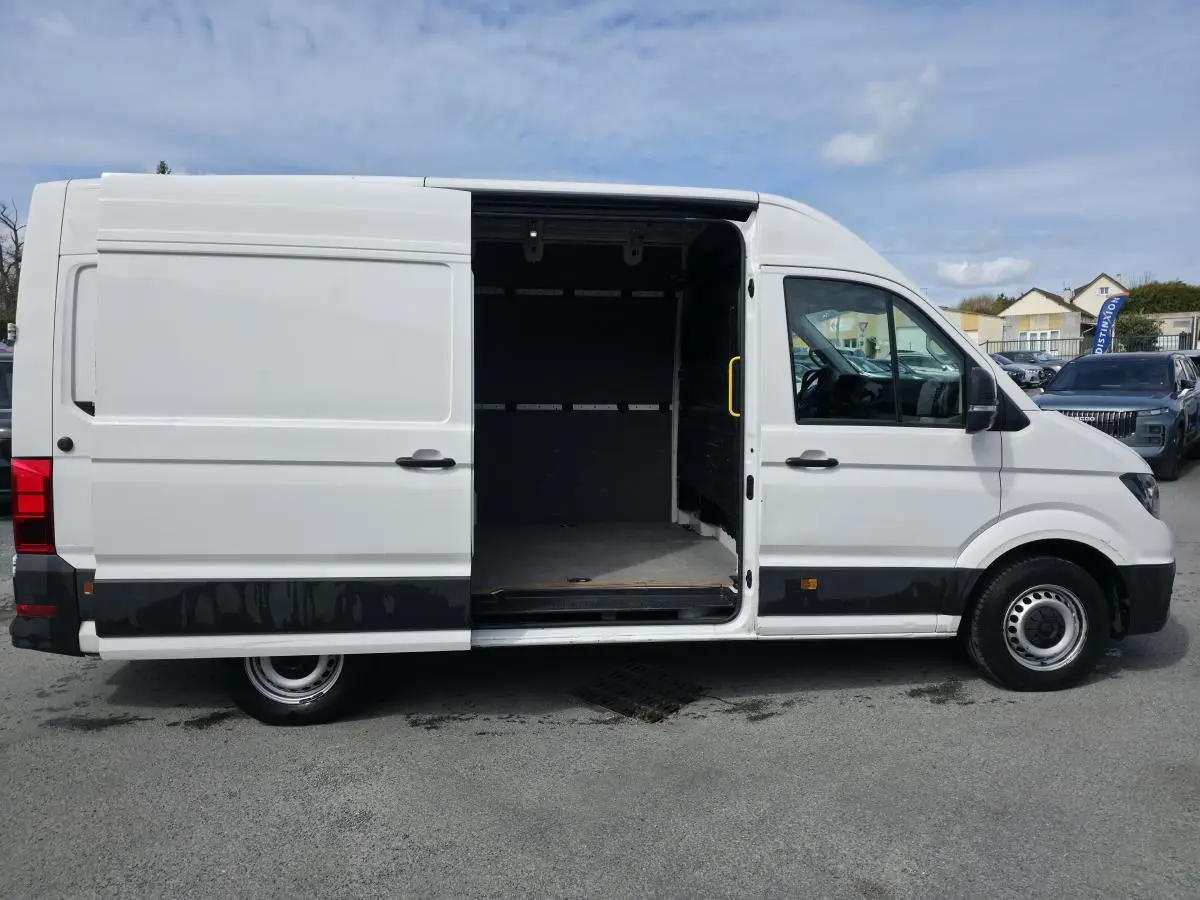 Vue latérale gauche d’un Volkswagen Crafter blanc avec porte coulissante ouverte montrant l’espace de chargement vide.