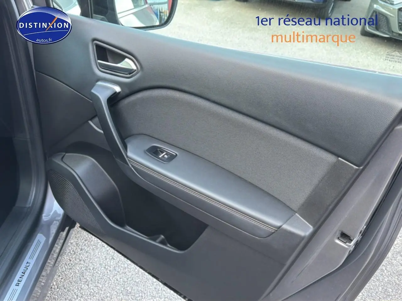Vue intérieure côté gauche de la porte avant grise du Renault Symbioz 2025 avec poignée et bouton de lève-vitre.