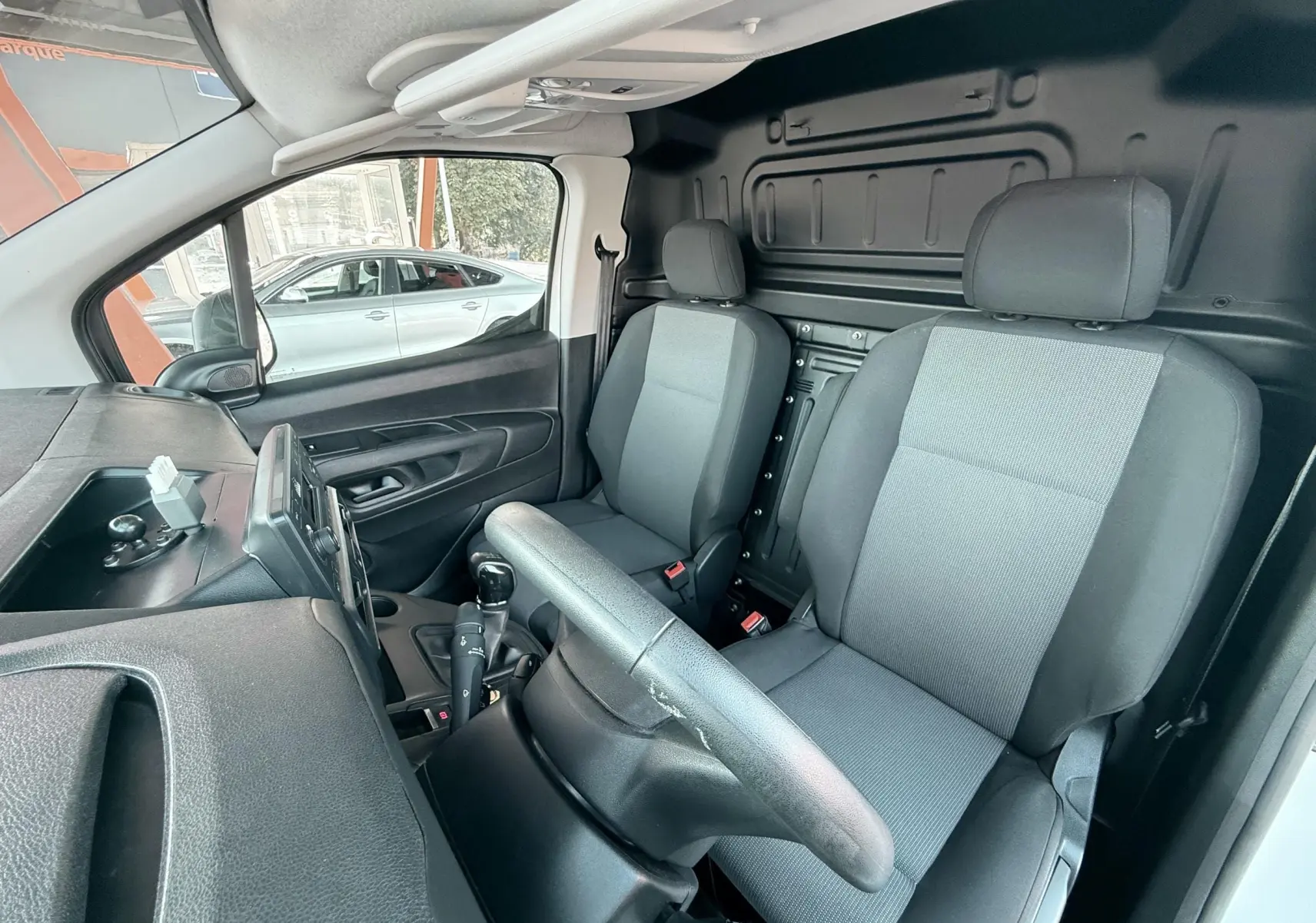 Vue intérieure côté conducteur du Citroën Berlingo blanc 2019, montrant les sièges gris et le tableau de bord simple.