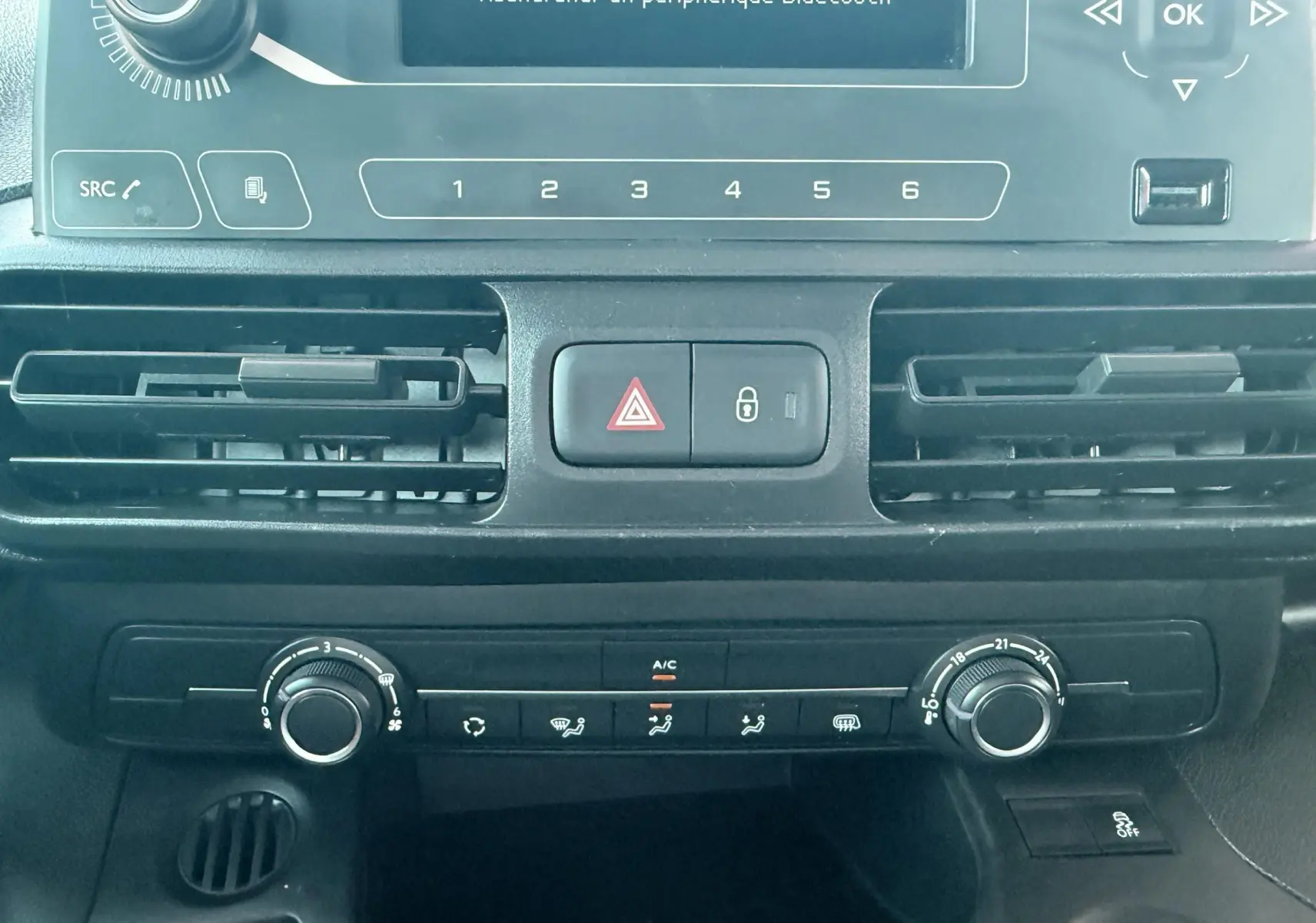 Vue rapprochée du tableau de bord noir du Citroën Berlingo 2019, montrant les commandes de climatisation et l’écran central.