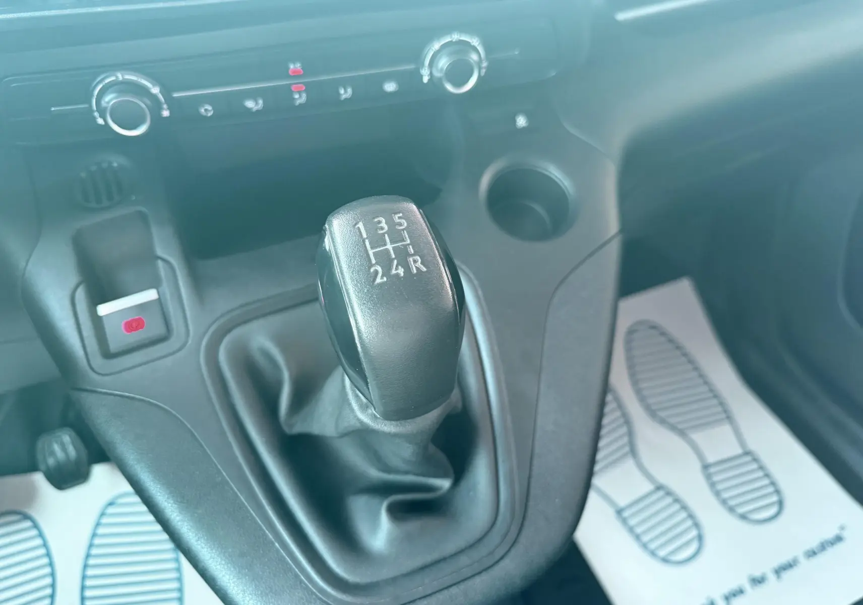 Gros plan sur le levier de vitesses manuel noir du Citroën Berlingo blanc 2019, avec console centrale et commandes visibles.