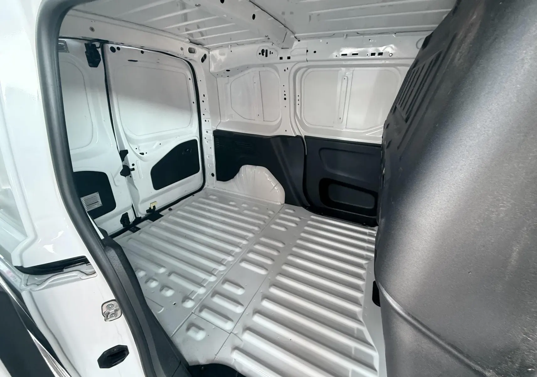 Vue intérieure de la zone de chargement arrière du Citroën Berlingo blanc 2019, version utilitaire, avec parois métalliques apparentes.