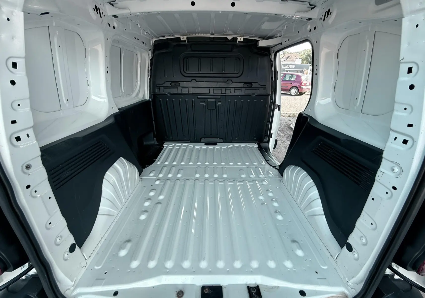 Vue intérieure arrière du Citroën Berlingo blanc 2019, montrant l’espace de chargement vide avec parois métalliques.