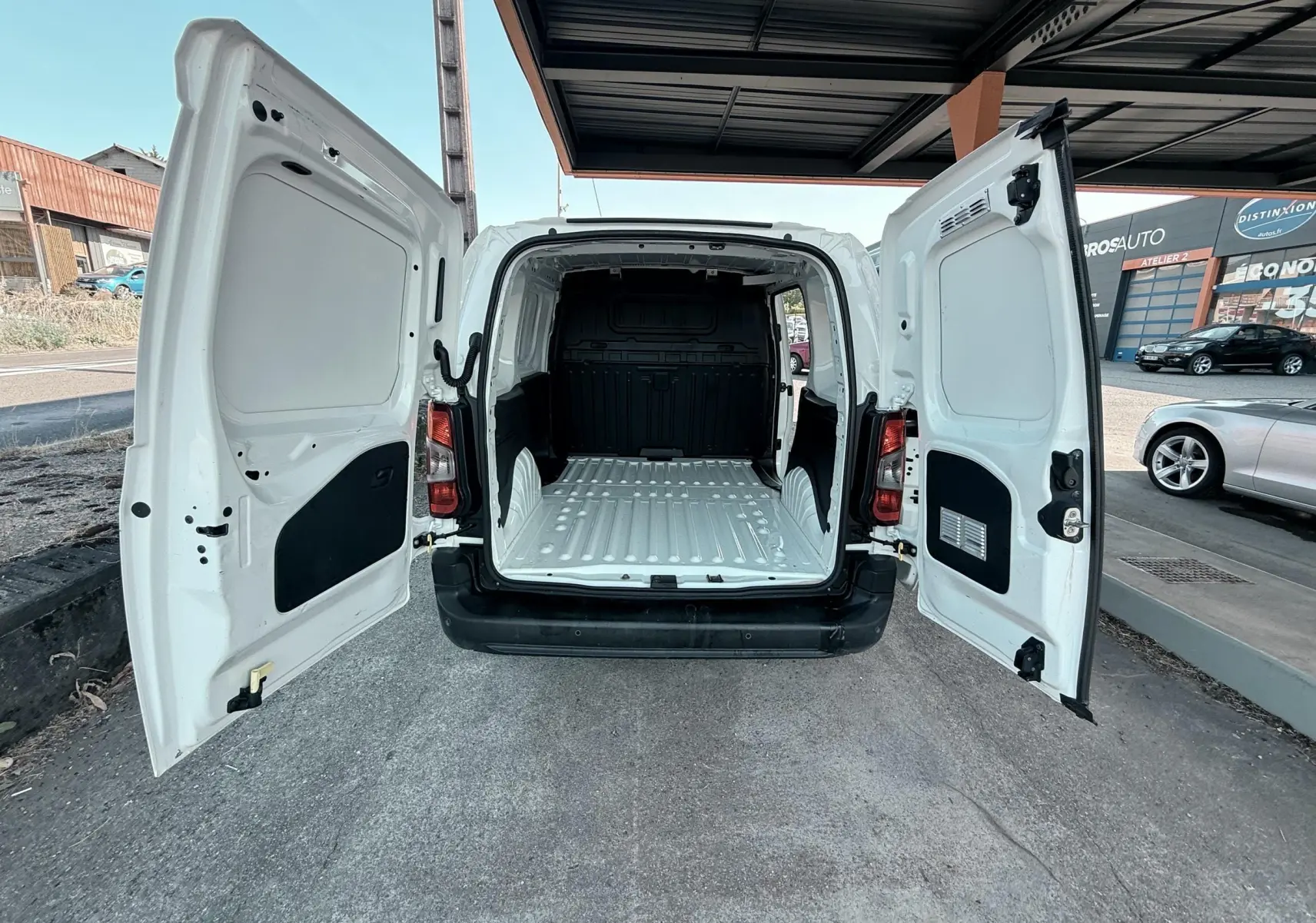 Vue arrière du Citroën Berlingo blanc 2019 avec portes ouvertes montrant l’espace de chargement vide et la carrosserie intérieure.
