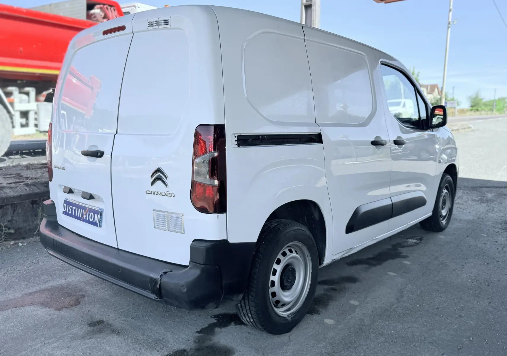 Vue 3/4 arrière droite d’un utilitaire Citroën Berlingo blanc avec pare-chocs noir et jantes acier.