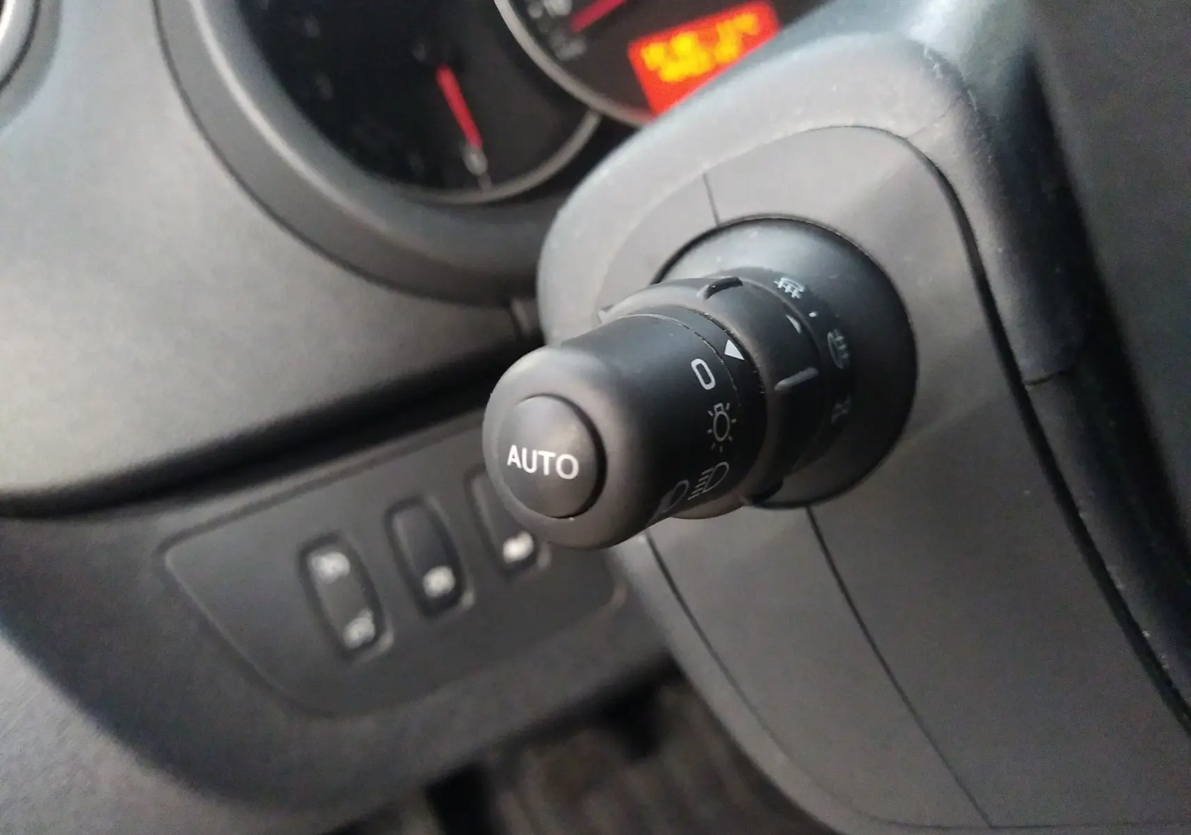 Gros plan sur la commande d’éclairage noire avec bouton AUTO dans l’habitacle du Renault Kangoo blanc 2019.