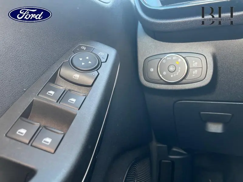 Détail des commandes de réglage des vitres et des phares sur la porte côté gauche d'une Ford Fiesta bleu azur 2022.