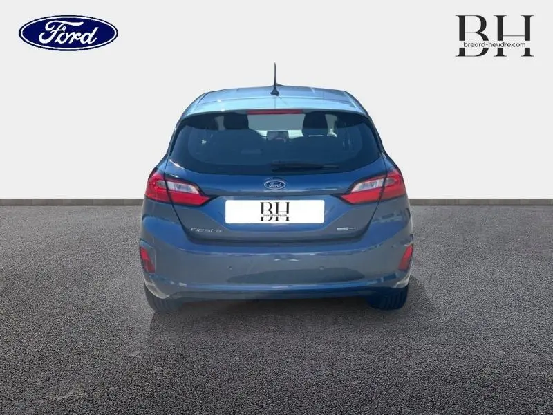 Vue arrière d'une Ford Fiesta 2022 bleu azur métallisé avec feux LED et becquet arrière visible.