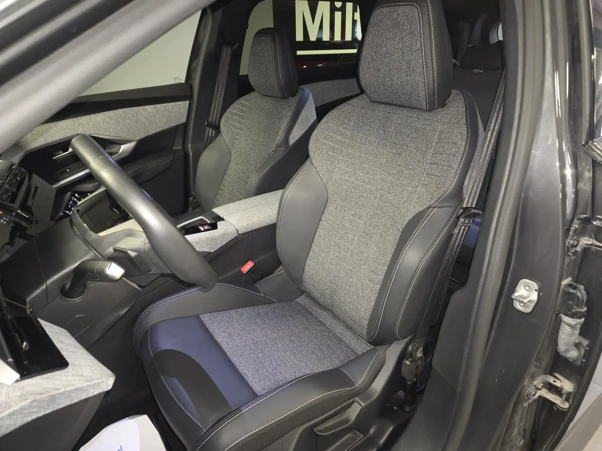 Vue intérieure côté conducteur du Peugeot 5008 gris 2025, sièges tissu gris et cuir noir avec surpiqûres contrastées.