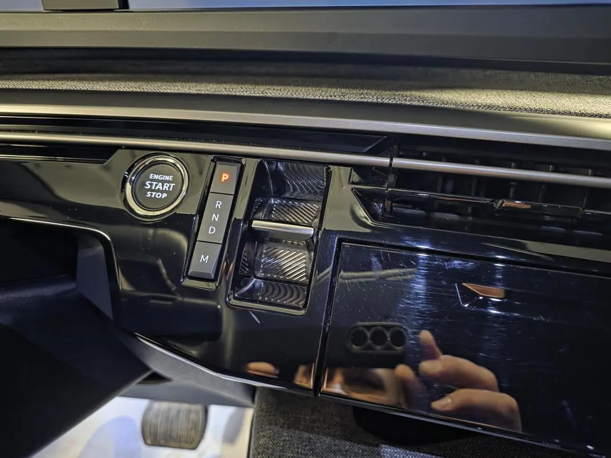 Détail de la console centrale noire laquée avec bouton start/stop et sélecteur de boîte auto du Peugeot 5008 gris hybride 2025.