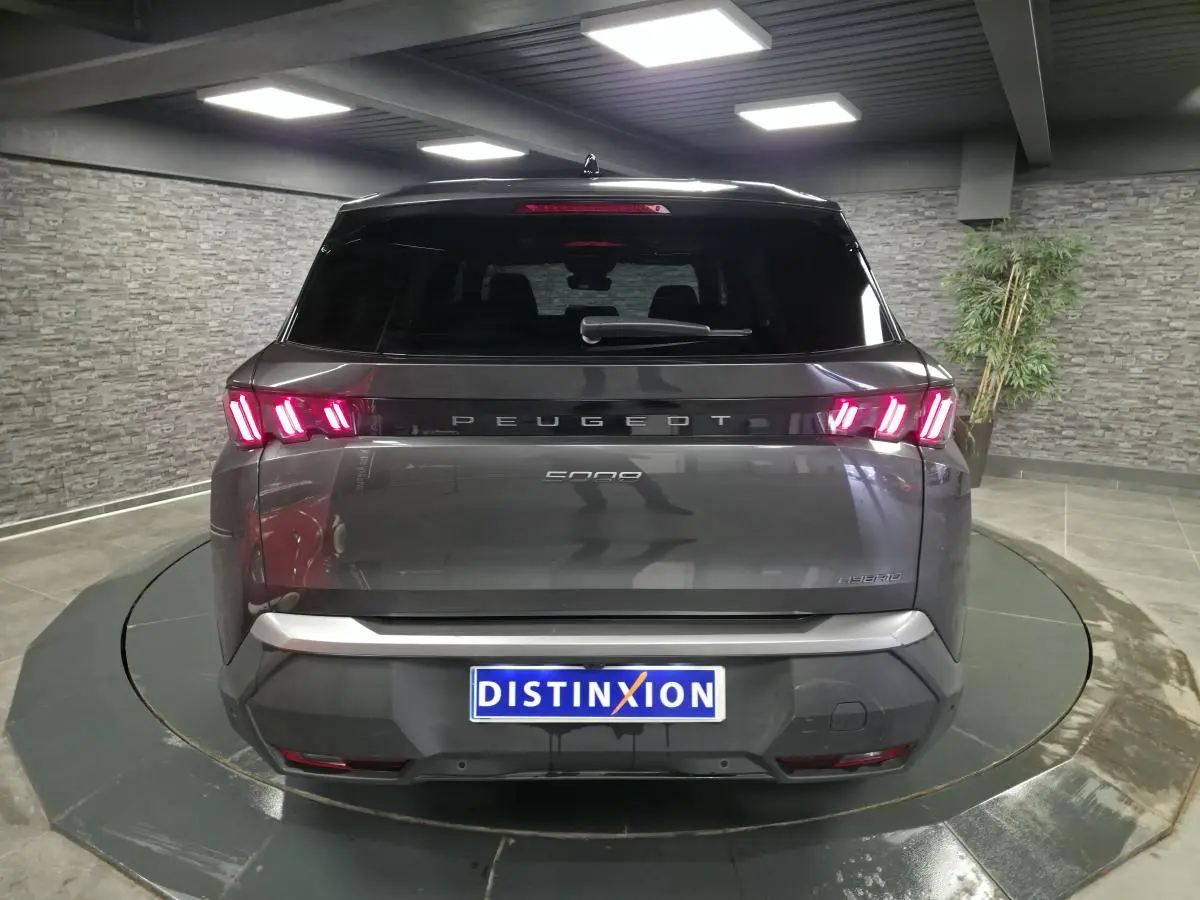 Vue arrière d'un Peugeot 5008 gris métallisé avec feux arrière LED en forme de griffes et bandeau noir laqué.