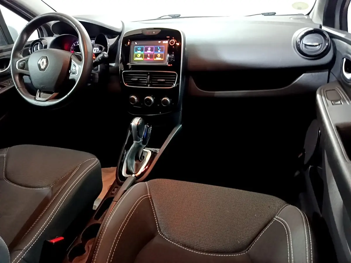 Vue intérieure avant droite de la Renault Clio Business 2018, volant cuir multifonctions et écran tactile central allumé.