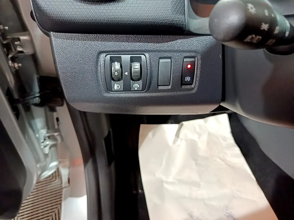 Vue rapprochée des commandes de réglage des phares et du système start-stop sur la Renault Clio Business gris clair 2018.