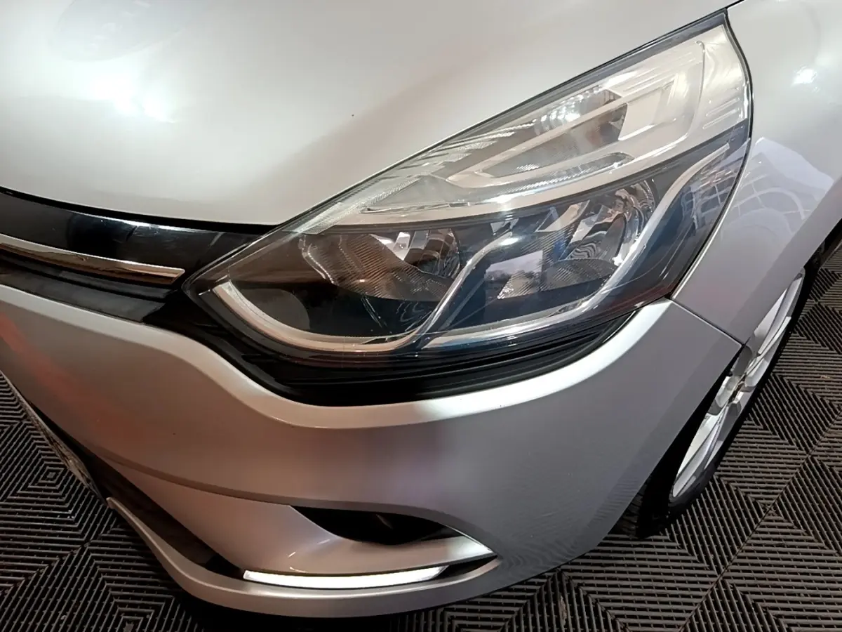 Gros plan sur l'avant droit gris clair de la Renault Clio 2018, mettant en valeur le phare et la calandre chromée.