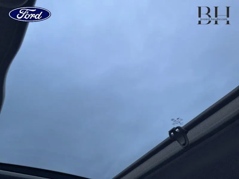 Vue intérieure du toit panoramique en verre d'une FIAT 500 Lounge gris métallisé, avec velum partiellement déployé.