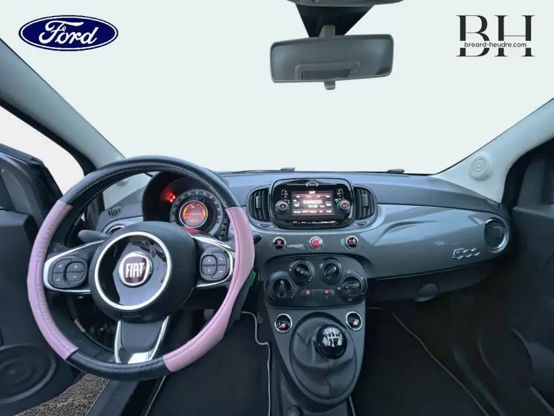 Vue intérieure avant de la Fiat 500 1.2 8v Lounge 2018 avec volant cuir bicolore et tableau de bord gris métallisé.