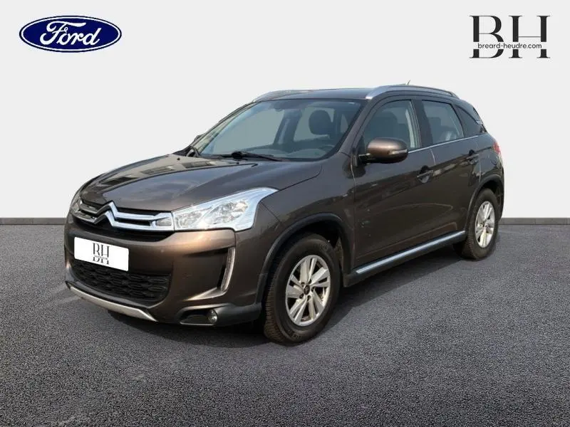 Citroën C4 Aircross brun Mangaro vue 3/4 avant droit avec calandre chromée et barres de toit visibles.