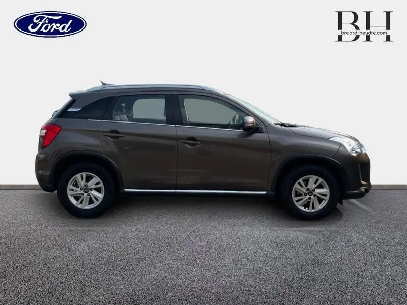 Profil droit d'un SUV Citroën C4 Aircross brun Mangaro avec jantes alu 16 pouces et barres de toit visibles.