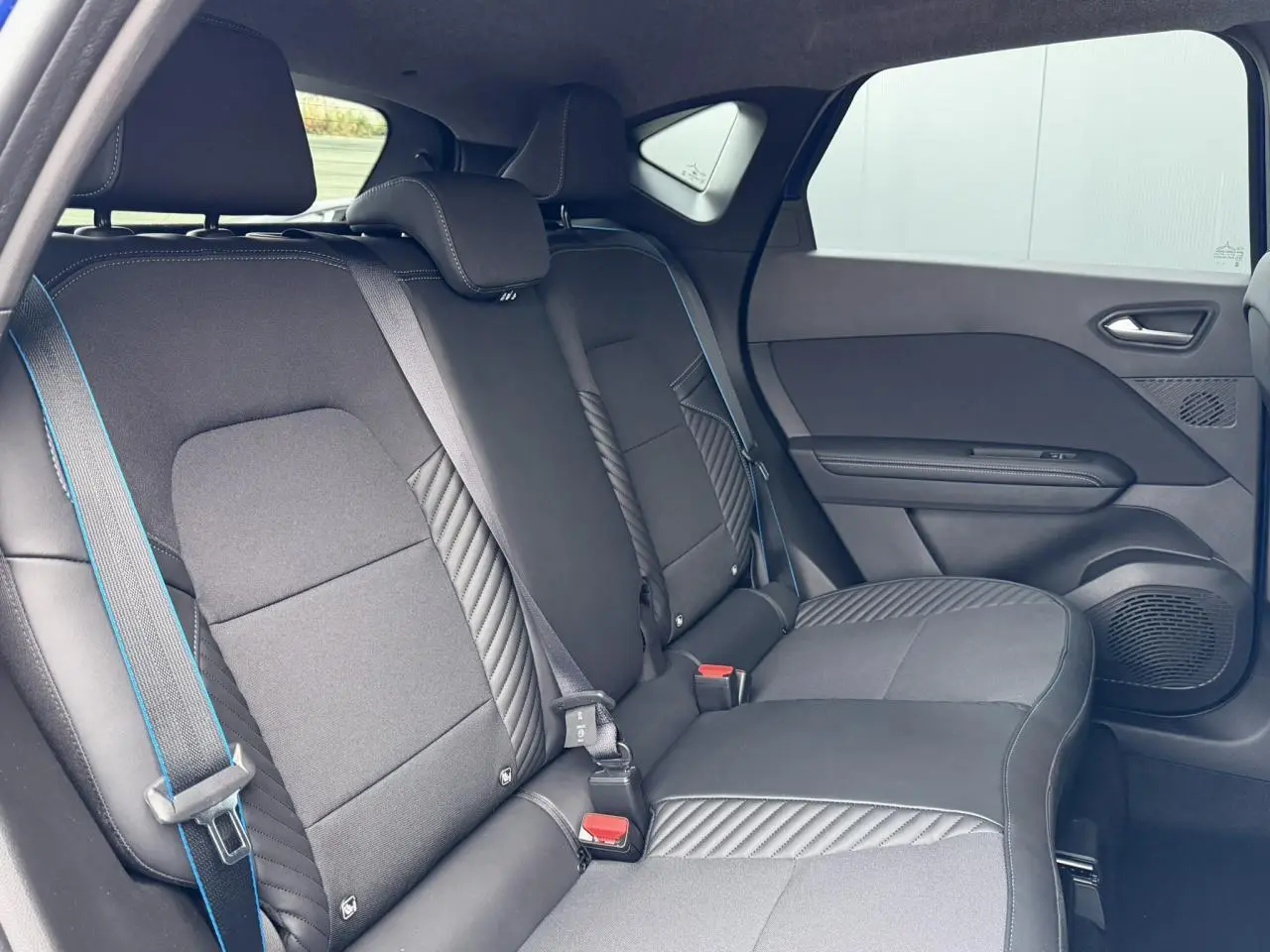 Vue intérieure côté droit des sièges arrière noirs avec surpiqûres bleues du Renault Captur Esprit Alpine 2025.