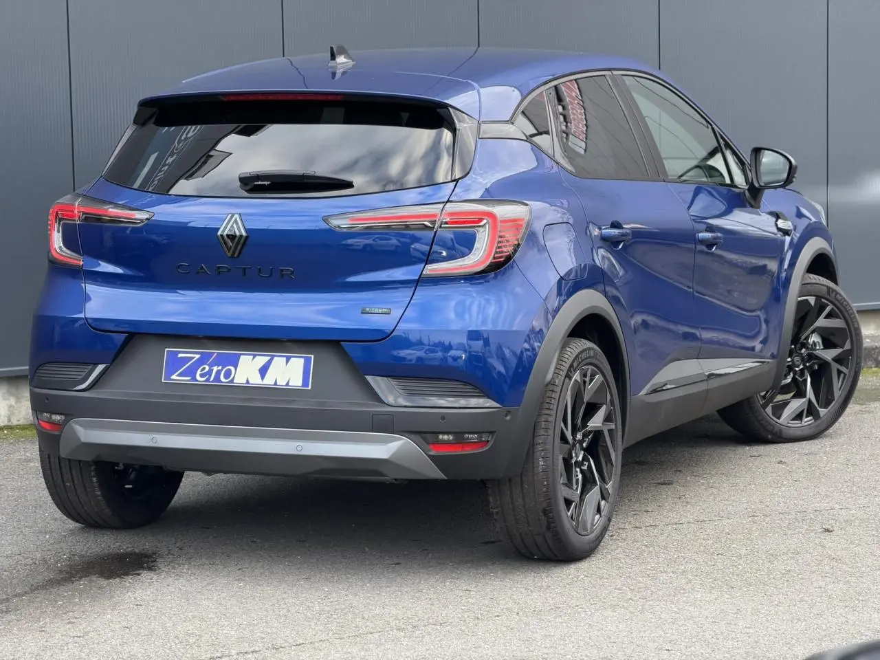 Vue 3/4 arrière droite du Renault Captur 2025 Bleu Iron avec jantes noires et vitres surteintées.