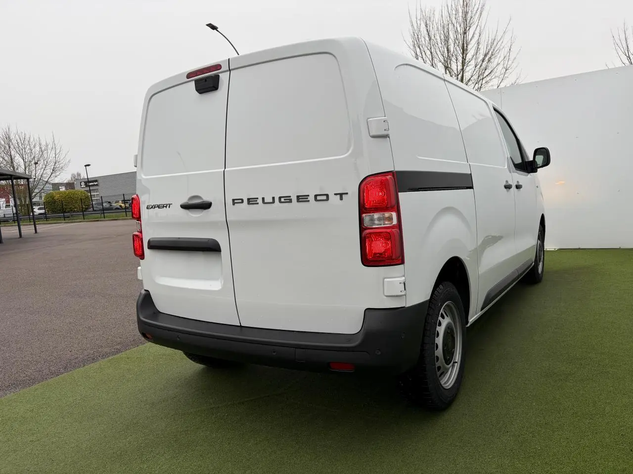 Vue 3/4 arrière droite du Peugeot Expert Fourgon blanc Icy avec jantes tôles grises et feux arrière rouges.